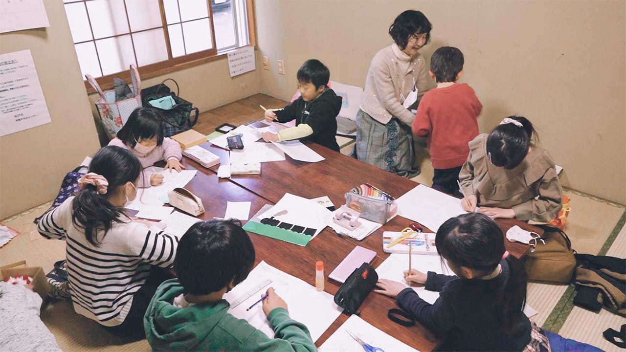畳の教室にある大きなテーブルで子どもの受講者が勉強に励んでいる写真